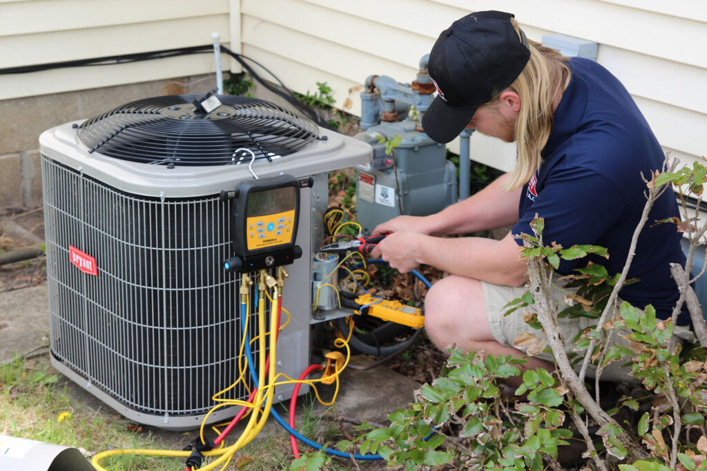 HVAC technician servicing outdoor air conditioner during Michigan heat wave
